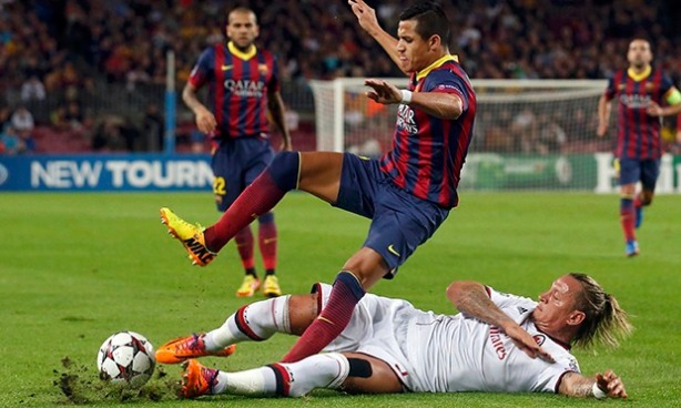 Barcelona's Alexis Sanchez is tackled by AC Milan's Philippe Mexes
